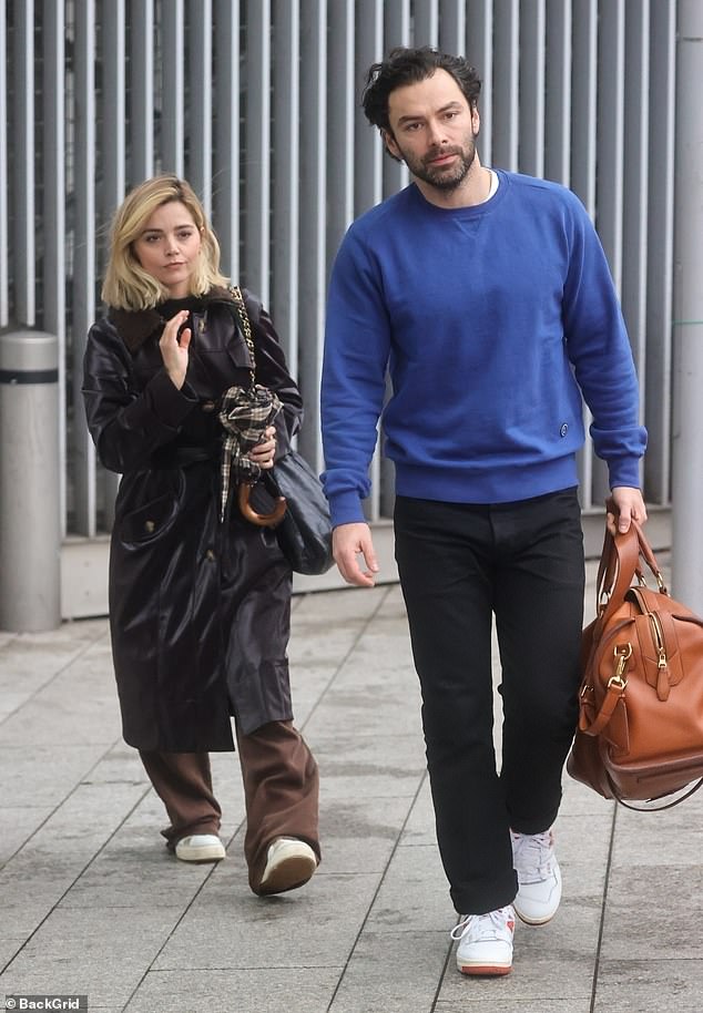 Stylish: The actress, 36, cut a modern figure when she dressed in a dark chocolate trench coat and trousers in a lighter shade, along with white sneakers (pictured with Aidan Turner)