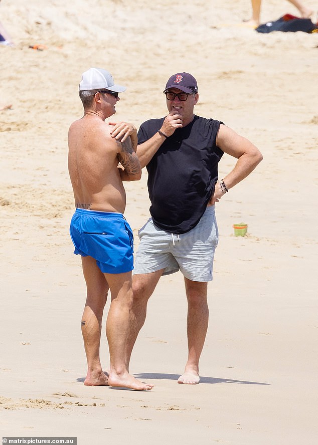 Michael showed off his various tattoos in a pair of blue swimming trunks while talking to Karl (right)