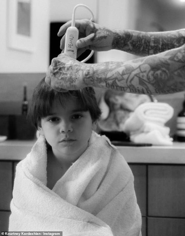 Moody: Kourtney's son Reign Disick, eight, looked gloomy as his head was shaved