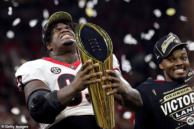 Jordan Davis #99 of the Georgia Bulldogs celebrates with the National Championship trophy after the Georgia Bulldogs defeated the Alabama Crimson Tide 33-18 during the 2022 CFP National Championship Game at Lucas Oil Stadium on January 10 -- No. 34 on the Sportico list