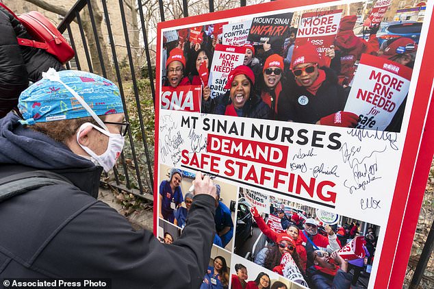 Zach Clapp, a nurse in the Pediatric Cardiac ICU at Mount Sinai Hospital, signs a sign demanding safe staffing during a rally by NYSNA nurses from NY Presbyterian and Mount Sina