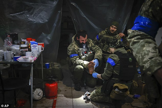 Ukrainian servicemen administer first aid to a wounded soldier in a shelter in Soledar, the site of heavy battles with Russian forces in the Donetsk region, Ukraine, Sunday, Jan. 8, 2023