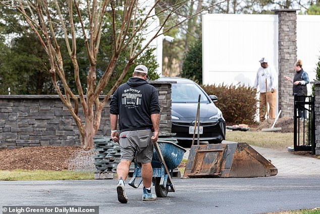 A worker pushes a wheelbarrow of materials toward Biden's beach home as a wall is built around the entire property