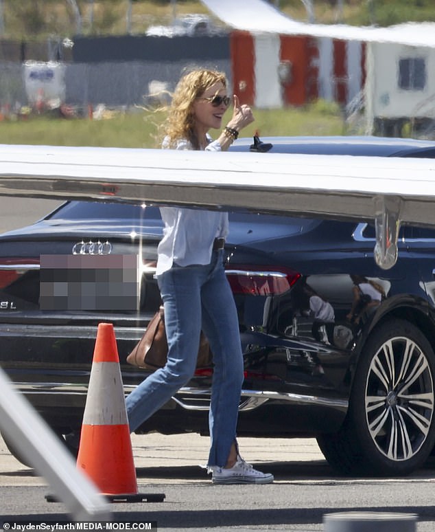 Nicole cut a casual figure in a pair of blue jeans along with a white blouse and shirt and a pair of Converse shoes.  She carried a tan bag