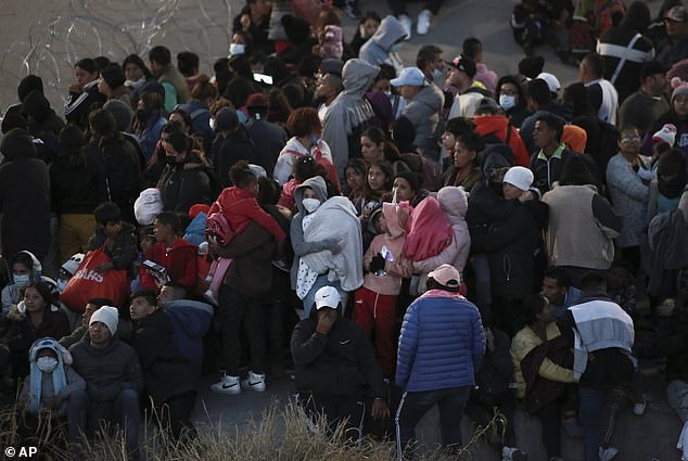 Migrants stand behind barbed wire to prevent them from crossing into El Paso, Texas, as seen from Ciudad Juárez, Mexico, on Tuesday.  The White House wants people to apply for asylum online