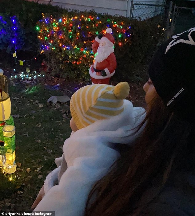 Embracing the season: In another cute snap, the producer was photographed holding her daughter as they looked at the colorful Christmas lights in the neighborhood