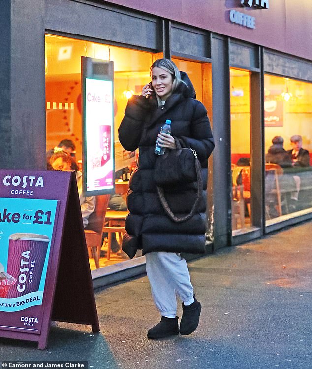 Keeping it casual: The former Love Island star bundled up against the cold and wet January weather in a long black puffer coat while wearing a casual gray tracksuit