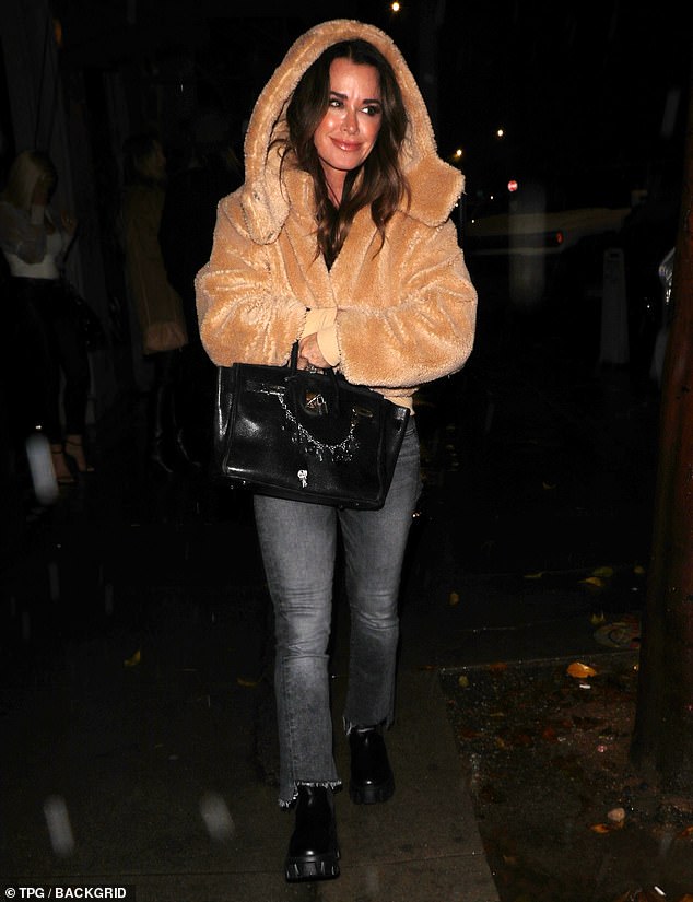 Hoodie: The Real Housewives of Beverly Hill star styled her brunette locks in long, flowing layers, protecting it from the rain by covering it with the hood of her jacket and carrying a black bag