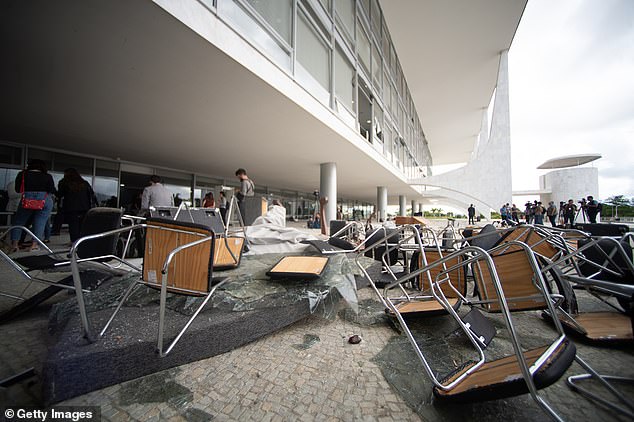 Workers clear debris caused by radical supporters of former President Jair Bolsonaro after a riot Sunday at the Planalto Presidential Palace