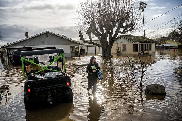 Brenda Ortega, 15, retrieves items from her flooded home in Merced, California, on Tuesday.  After days of rain, Bear Creek overflowed its banks, leaving dozens of homes and vehicles surrounded by floodwaters.