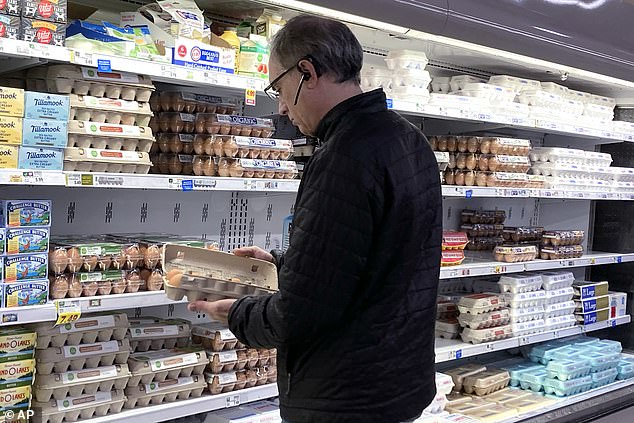 A shopper checks eggs before shopping at a grocery store in Glenview, Illinois, on Tuesday.  Anyone shopping for a dozen eggs these days will have to be prepared for sky-high prices.