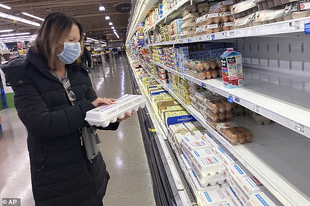 A shopper checks eggs before buying them at a grocery store in Glenview, Illinois, on Tuesday.