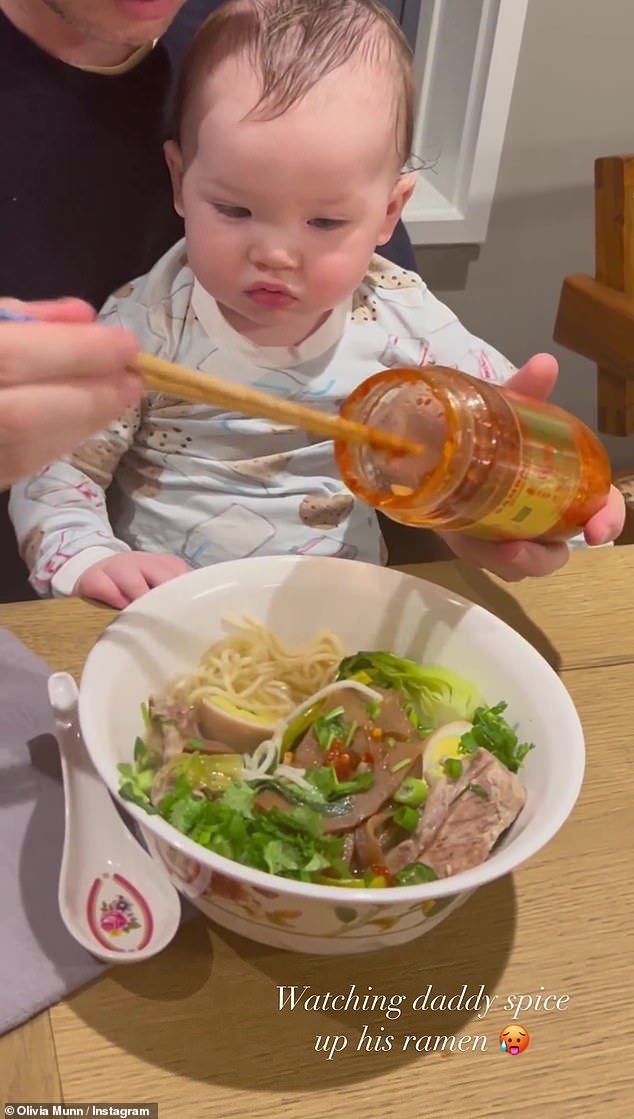 Front row seat: Malcolm sat on the comedian's lap as he used chopsticks to mix the sauce into the noodles and broth.