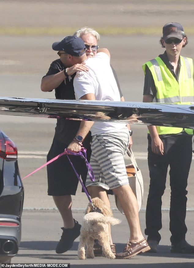 Happy to be home from his vacation in Port Douglas, the co-host of The Kyle and Jackie O Show greeted his manager Bruno Bouchet with a hug as they held onto the leashes of their two poodles.