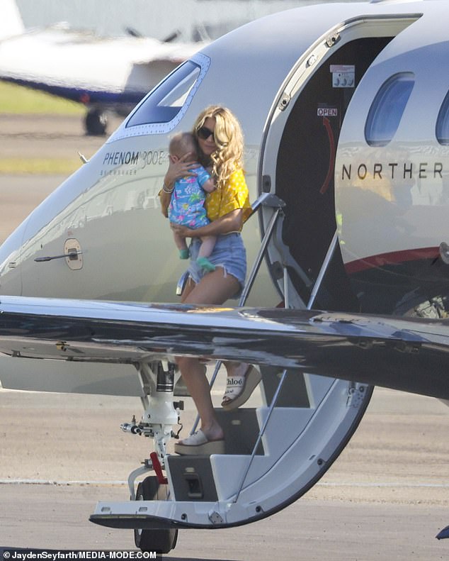 Slipping on her own pair of dark sunglasses, she donned a summery look with a yellow cropped shirt and Daisy Duke jean shorts.