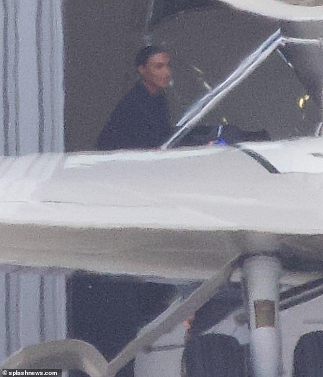 Wheels up: Kim smiled as she walked up the steps with her raven hair tied back and her baggy clothes.