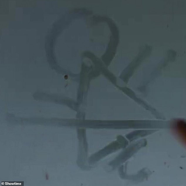 Unknown: The show's mysterious cult symbol, resembling a drawing of a person impaled, is seen ominously traced on a misted window.