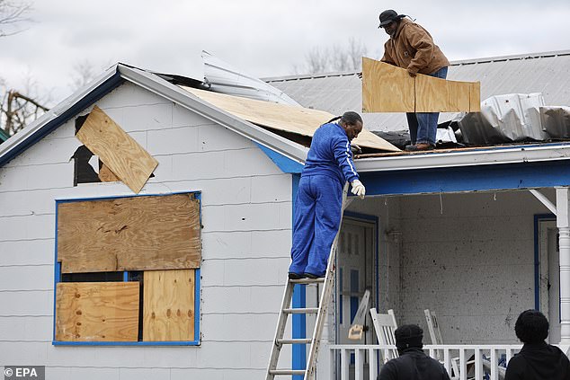 People work to board up the roof and windows of a damaged home in Selma on Friday.