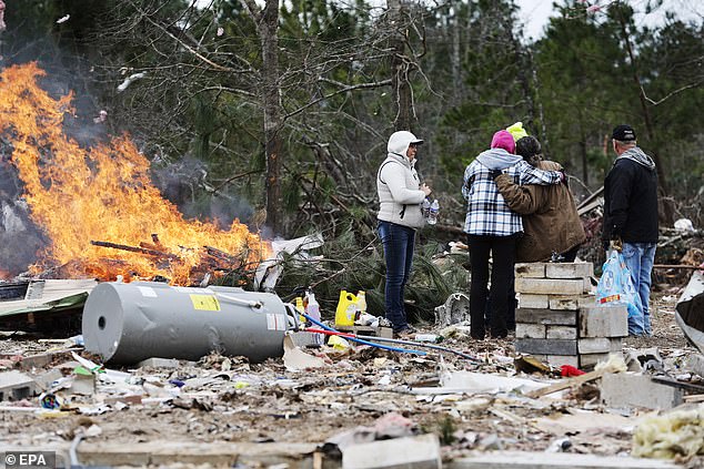 People burn debris from their homes as they clean up after the tornado in Old Kingston, Pratville, Alabama