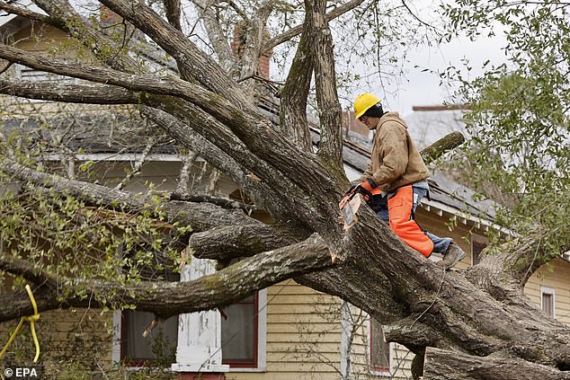 A man with a chainsaw tries to clear debris from a house in Selma on Friday, after the devastating series of storms.