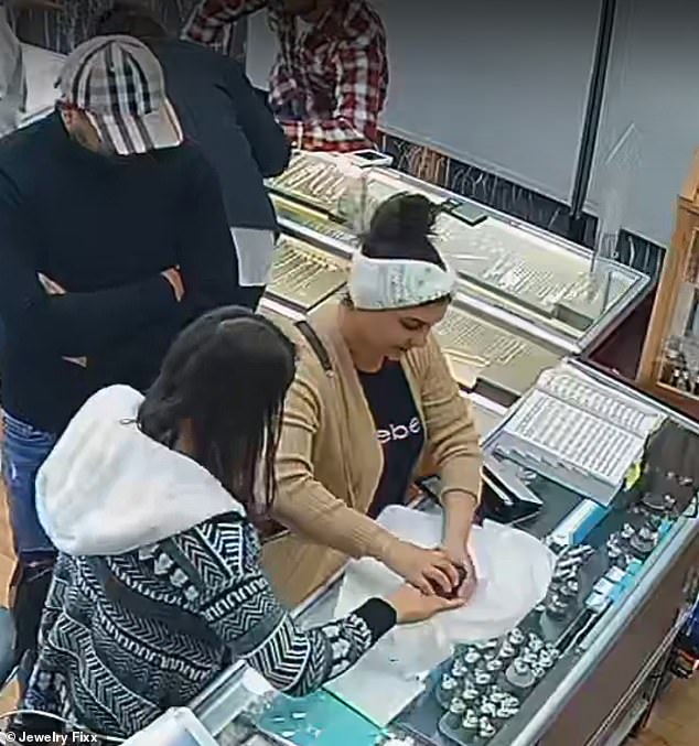 Both women are seen here at the counter playing with the empty box they were placing on the tissue paper while the stolen ring was in the woman's hand.