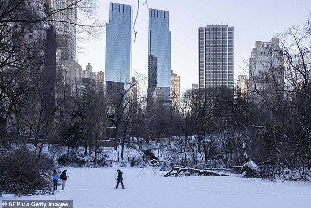 People walk along a frozen lake in New York's Central Park on January 30, 2022, days after a blinding storm hit New York causing power outages and traffic delays.