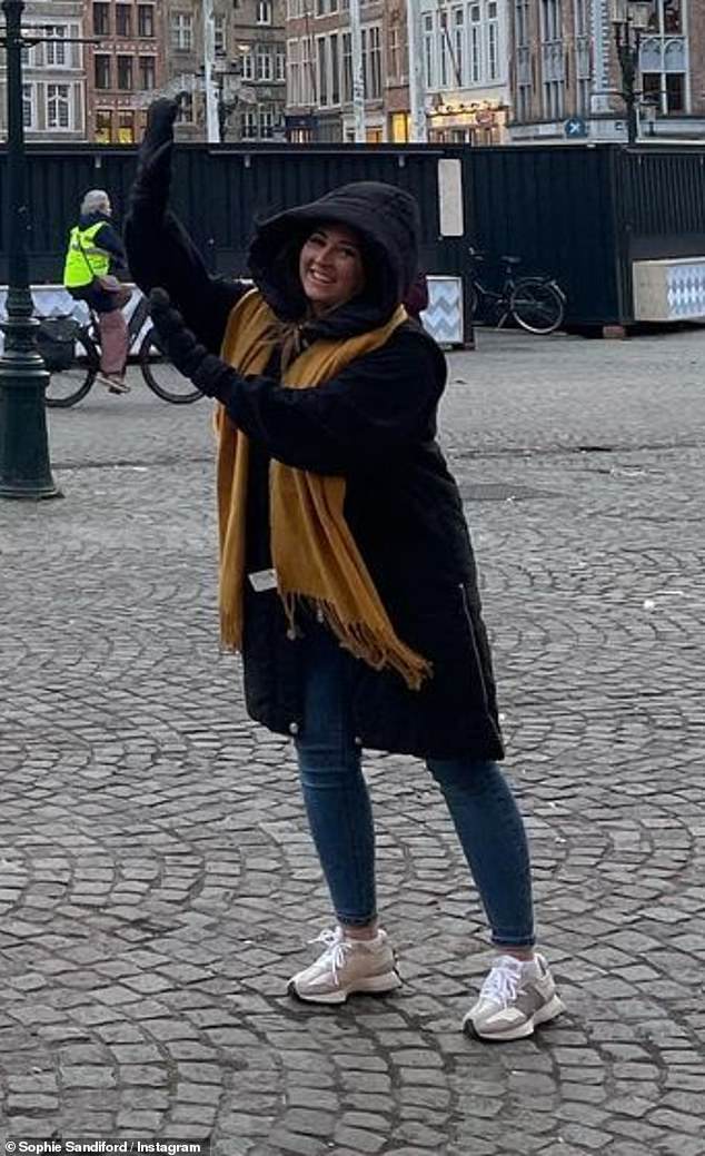 Tourist: The brunette beamed in front of the Belfry of Bruges while jokingly holding up her hands to pretend to hold the bell tower