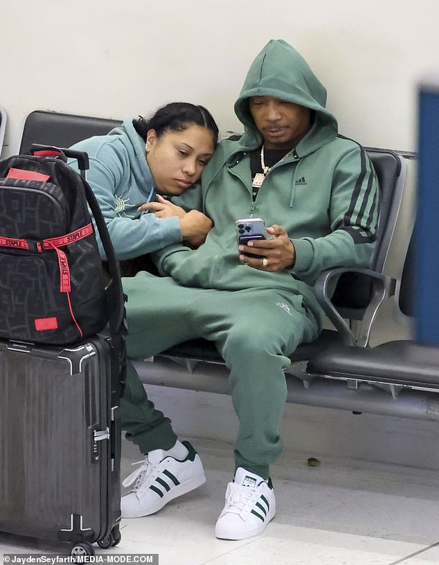 The star relaxed with his wife Aisha Atkins on a bench as they waited for their transfer to the airport.