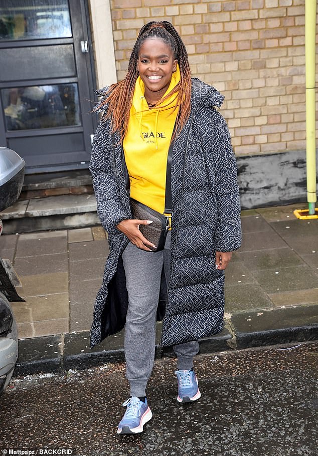 Beaming: Flashing a smile for the camera, she paired the look with a pair of blue sneakers, draping a crossbody bag over her torso