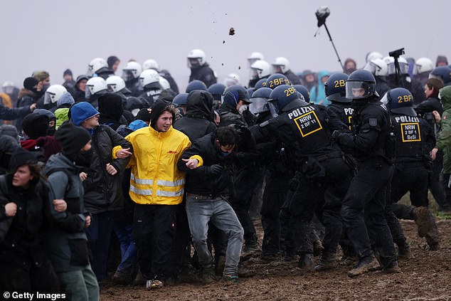 Protesters link arms as riot police confront them outside the mine on Saturday, January 14.