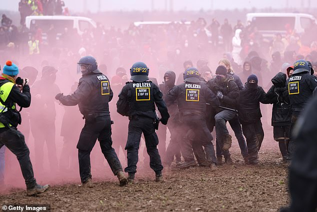 Smoke wafts through the air as eco-activists scuffle with police outside the mine on Saturday, January 14.