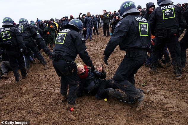 A protester falls to the ground during clashes between police and eco-activists at the coal mine on Saturday, January 14.