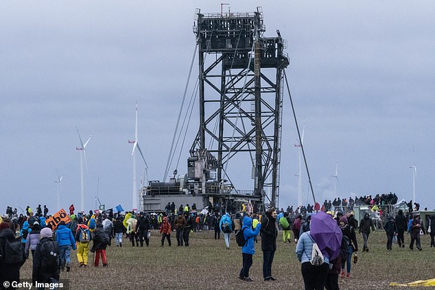 Protesters gather in a field next to the mine as a huge piece of mining equipment looms in the background on Saturday, January 14.