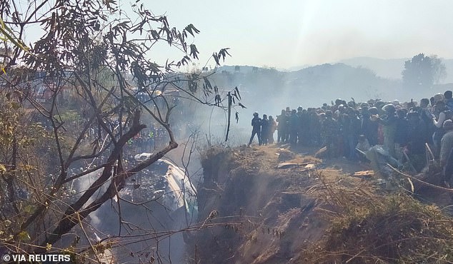 Crowds gather at the crash site of a plane carrying 72 people in Pokhara, western Nepal.