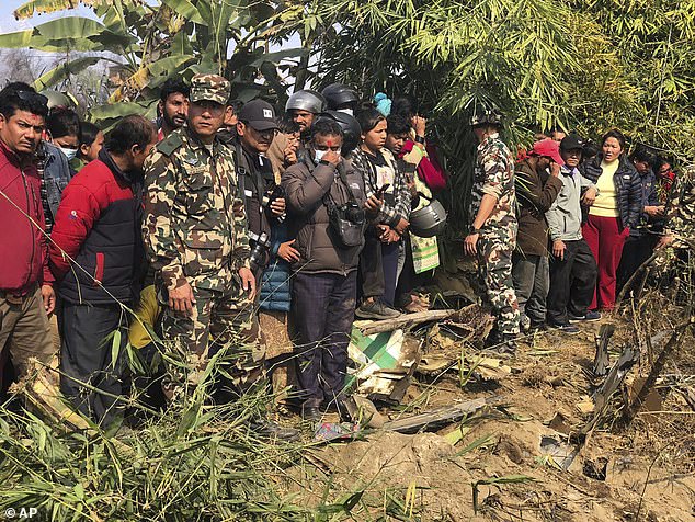 Neighbors look at the wreckage of a passenger plane in Pokhara