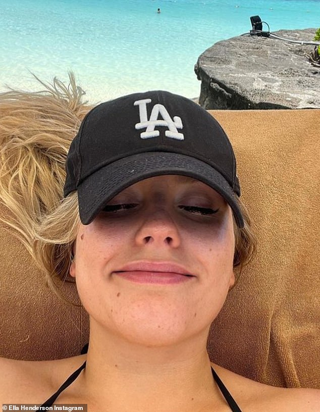 Laid back: She looked in high spirits as she lounged on a poolside lounger showing off her natural beauty beneath a black baseball cap