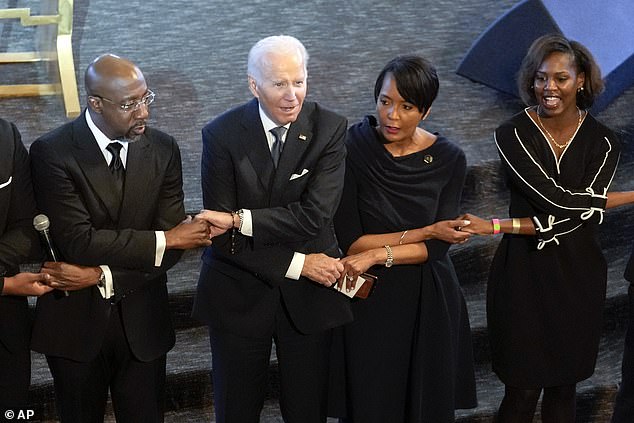 The president crossed his arms with several people, including Warnock and White House adviser Keisha Lance Bottoms, as he sang 