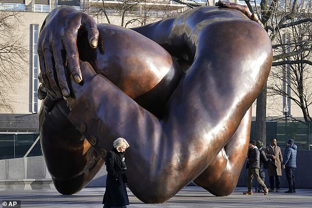 Passersby walk near the 20-foot-tall bronze sculpture "Hug," A memorial to Dr. Martin Luther King Jr. and Coretta Scott King, on the Boston Common, Tuesday, Jan. 10, 2023, in Boston