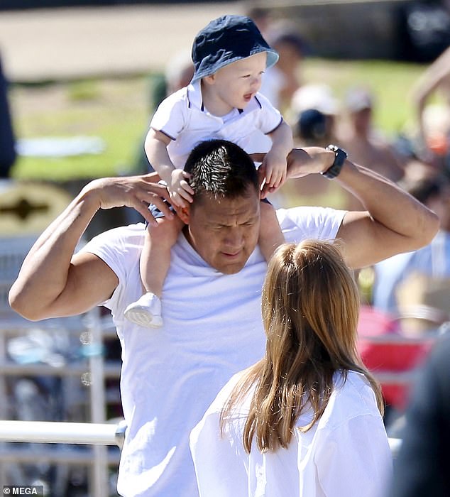 The Singapore-based star's stocky build and bulging biceps were visible under his shirt as he hoisted his little one onto his shoulders.