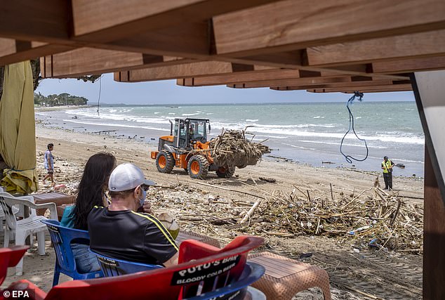 A familiar sight along Bali's east coast in summer: tractors cleaning up the beach