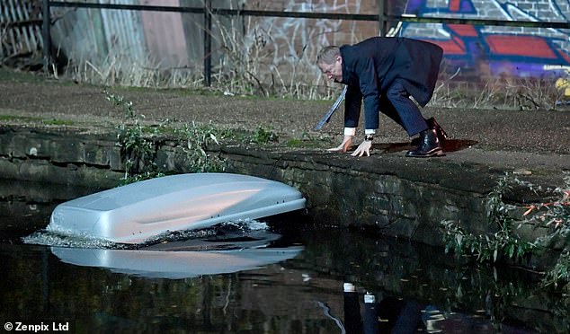 This can't be good: Placing some rubble next to the corpse, he pushes a roof box into the water, much to his relief.