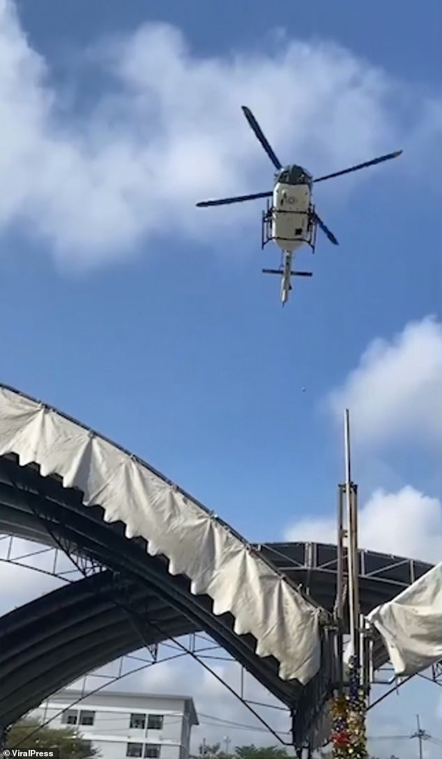 From another angle, small objects can be seen falling from the helicopter above the crowd.