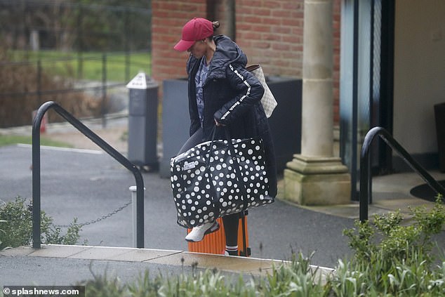 Back to reality: On Monday morning, Michelle donned a red baseball cap and puffer coat as she headed home from her hotel, juggling a massive suitcase and several bags.