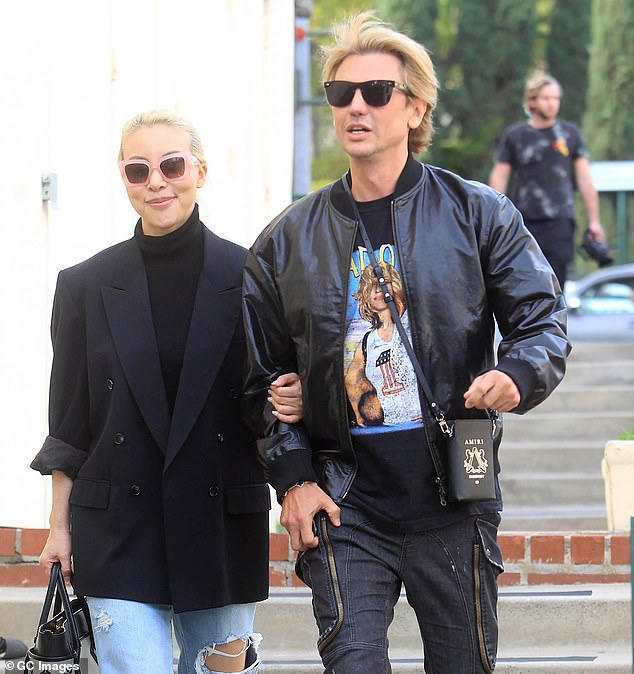 Cute duo: Her friend had light hair and wore a dark blazer over a dark top with ripped jeans and black Louis Vuitton sneakers.