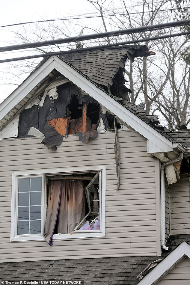 The house was seen partially destroyed by fire.  Smoke filled curtains hung outside a broken window