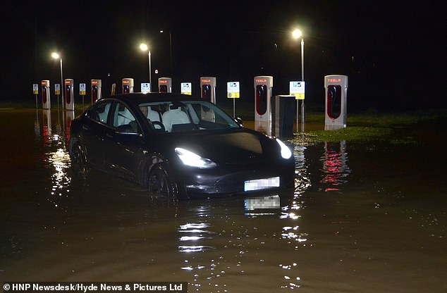 As these photos taken by a passerby near the hotel in Sindlesham, near Reading, Berkshire, show, the driver was caught in the middle of the floodwaters that inundated the hotel grounds and the Tesla charging area after the nearby River Loddon erupted.  benches and poured millions of gallons of water into the hotel grounds.  Nearby roads, only a few feet away, were made impassable by the waist-high water