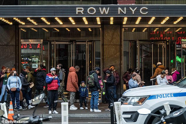 People wait for children returning from school at the Row hotel in Manhattan, which is used to house immigrants.