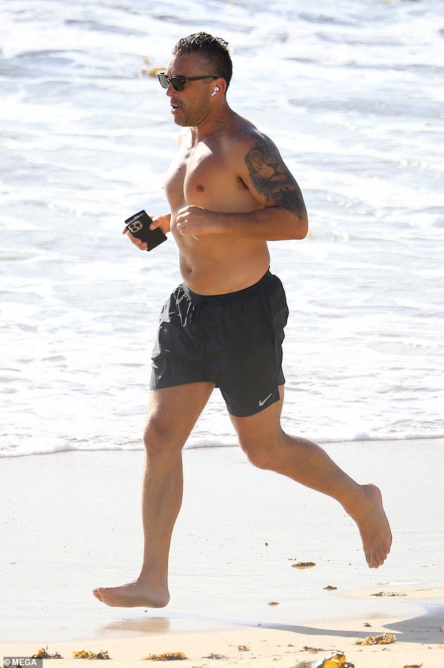 The former Roosters player showed off his tattooed biceps as he ran through both wet and dry sand