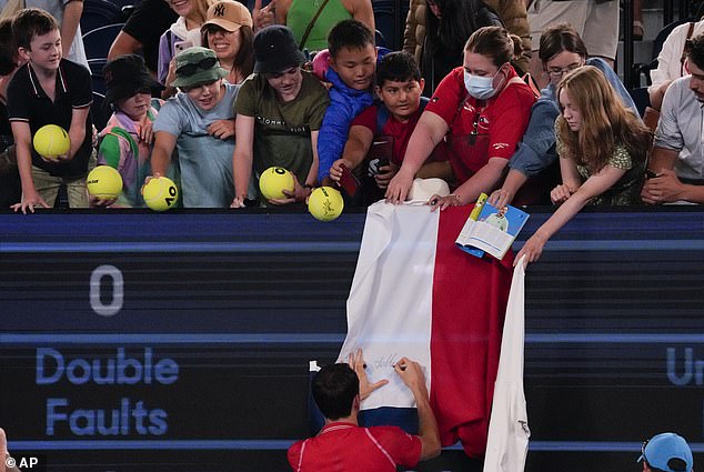 Daniil Medvedev of Russia signs a banner for a fan after defeating Marcos Giron of the USA in their first round match at the Australian Open