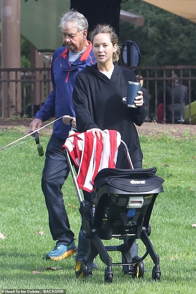 Staying cool: The Oscar winner held a blue mug in her hand from which she drank as she pushed a stroller across the park's green grass